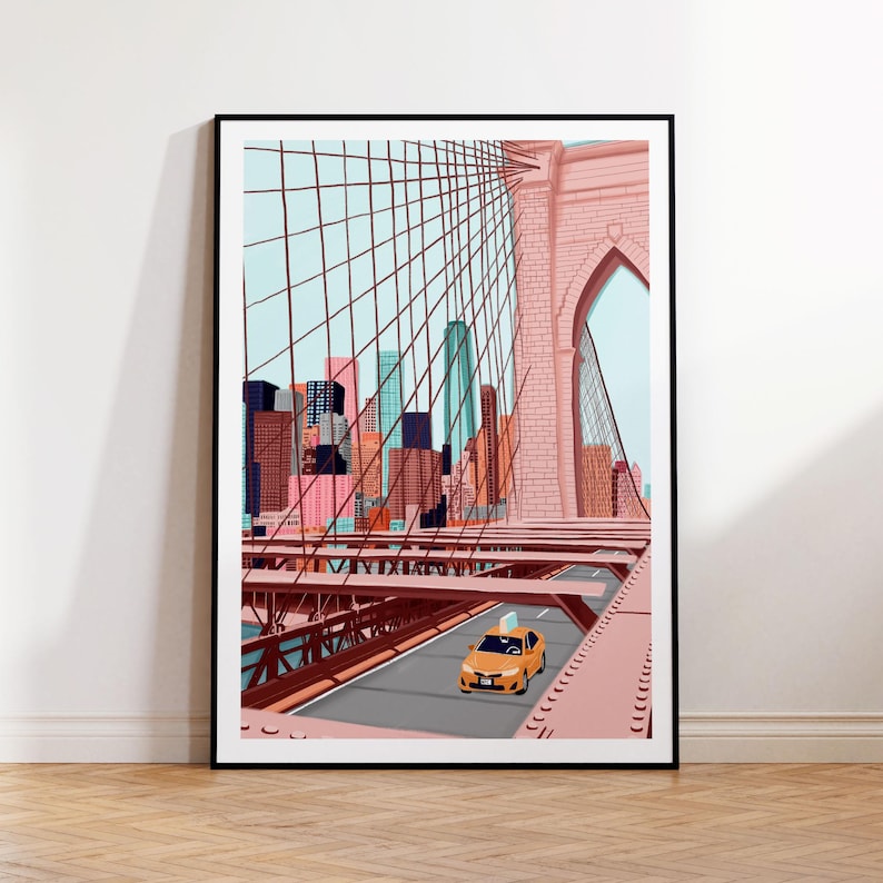 May include: Framed art print featuring a stylized illustration of the Brooklyn Bridge in New York City. The artwork showcases the bridge's pinkish-red structure, a yellow taxi, and a cityscape backdrop with colorful skyscrapers. The print is in a black frame.