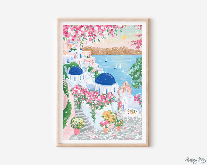 以下が含まれることがあります： 白い建物、青いドーム、鮮やかなピンクの花が特徴の、絵のように美しい海岸沿いの村を描いた額入りのアートプリント。このアートワークは、青い海、ヨット、背景の山々がある晴れた日を描いています。「Simply Katy」のサイン入りです。