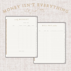 May include: Two open spiral-bound notebooks with beige pages. One is labeled "monthly BUDGET" and the other "BILL PAY checklist." The text "MONEY ISN'T EVERYTHING, it's just 99%" is written in gold script at the top. The notebooks have a neutral, minimalist design.