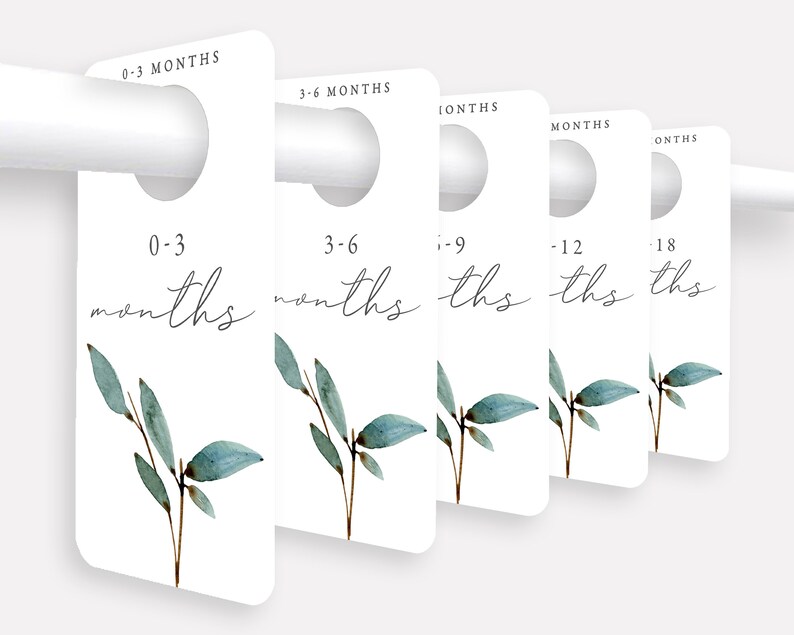 May include: Five white door hangers with a hole at the top for hanging. Each hanger has a different age range printed on it in black text: 0-3 months, 3-6 months, 6-9 months, 9-12 months, and 12-18 months. Each hanger has a watercolor illustration of a green leafy branch.