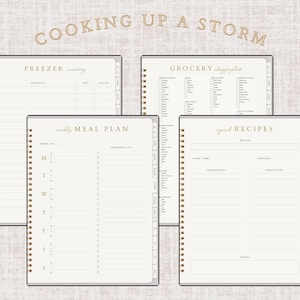 May include: A collection of spiral-bound notebooks with gold accents and cream-colored pages. The notebooks include sections for freezer inventory, grocery shopping lists, weekly meal plans, and special recipes. The words "COOKING UP A STORM" are printed at the top.