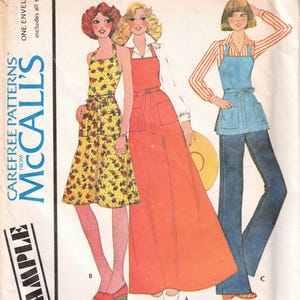 May include: A sewing pattern for a butcher apron with three different styles. The pattern includes a long red apron, a shorter yellow floral apron, and a blue apron with a white and red striped shirt. The pattern is from McCall's and is called "Carefree Patterns".