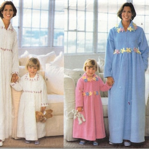 May include: Image of a pattern for matching adult and child robes. The adult robe is shown in white and blue, and the child's robe is shown in white and pink. The robes have floral accents and are long-sleeved.