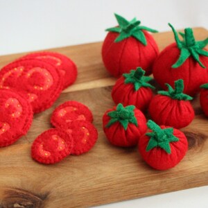 Pu&ograve; includere: Una collezione di pomodori e fette di pomodoro in feltro rosso con piccioli in feltro verde. Il set comprende diversi pomodori interi rotondi di varie dimensioni e molteplici fette piatte con dettagli cuciti in giallo.