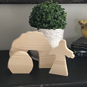 May include: Wooden Easter craft set with a tomb, a stone, and a figure of Jesus. The set is unpainted and ready to be decorated.
