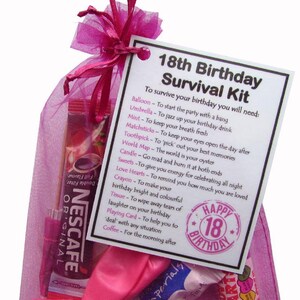 May include: A pink mesh gift bag containing an 18th Birthday Survival Kit. The kit includes a Nescafe coffee packet, sweets, a playing card, and a tag with a list of items. The tag reads "Happy 18th Birthday".