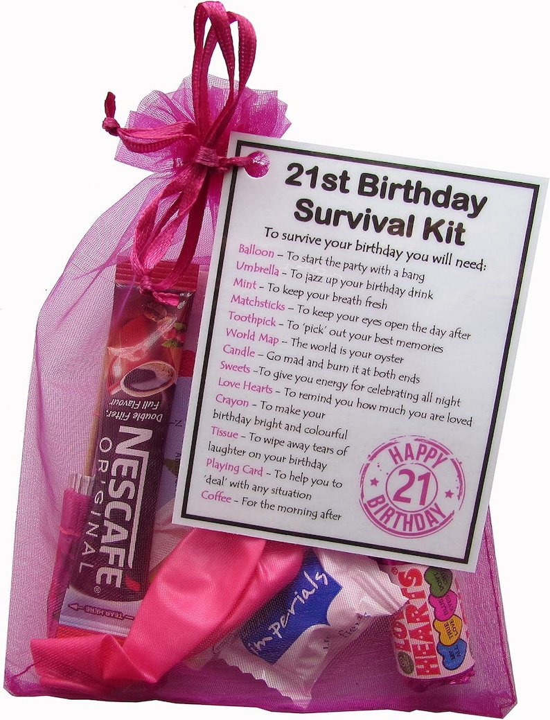 May include: A pink mesh bag filled with a 21st birthday survival kit. The kit includes a balloon, umbrella, mint, matchsticks, toothpick, world map, candle, sweets, love hearts, crayon, tissue, playing card, and coffee. The bag has a tag that reads "21st Birthday Survival Kit" and lists the items included in the kit.