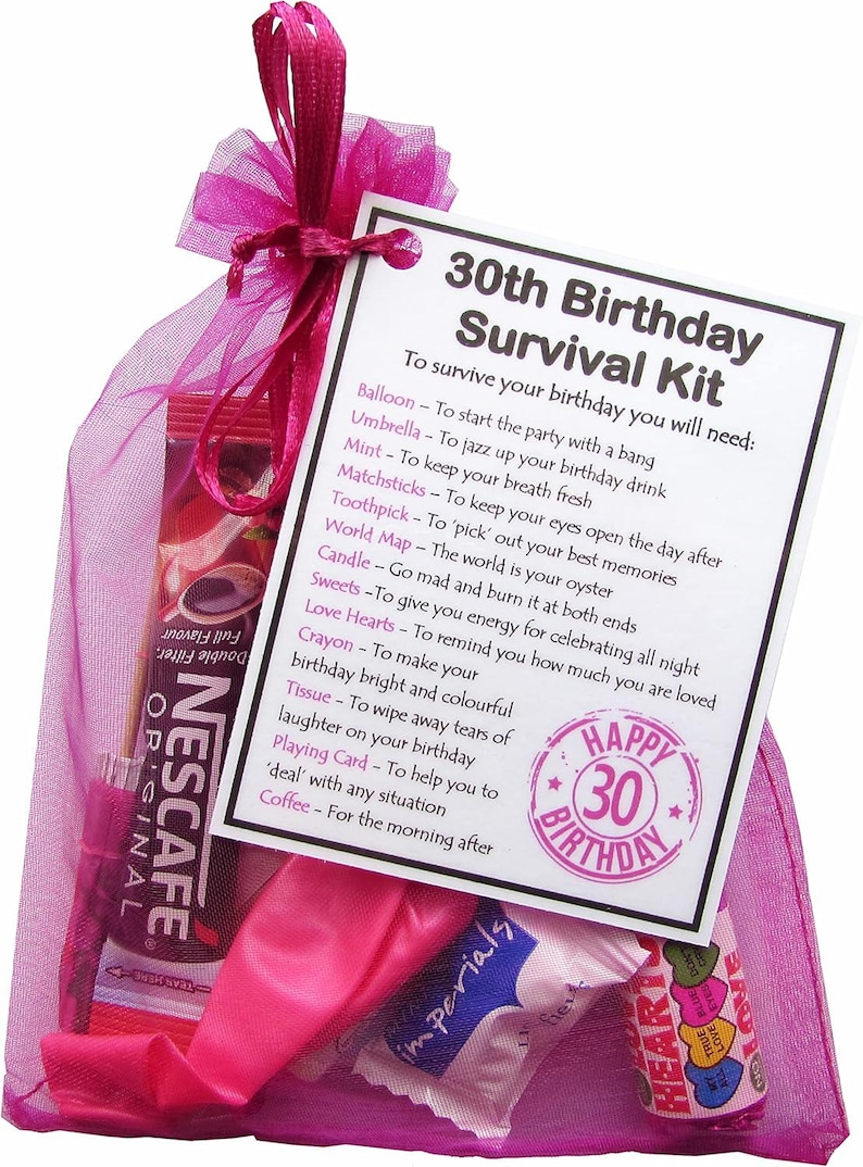 May include: A pink tulle bag filled with a birthday survival kit. The kit includes a balloon, umbrella, mint, matchsticks, toothpick, world map, candle, sweets, love hearts, crayon, tissue, playing card, and coffee. The bag has a tag attached that reads "30th Birthday Survival Kit" and lists the items included in the kit with their uses. The tag also has a Happy 30th Birthday stamp.