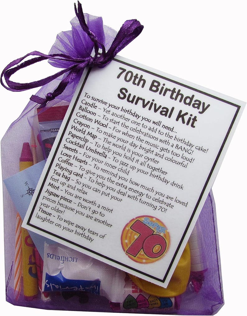May include: A purple organza bag filled with a 70th birthday survival kit. The kit includes a candle, balloon, cotton wool, crayon, world map, paperclip, cocktail umbrella, sweets, love hearts, coffee, playing card, tea bag, mint, jigsaw piece, and tissue. The bag has a white card attached with the text "70th Birthday Survival Kit" and a list of items needed to survive the birthday.
