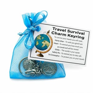May include: A blue organza gift bag tied with a ribbon, containing a travel charm keyring. The keyring features charms of a globe, a car, and a coin. A card with text and a globe illustration is attached.
