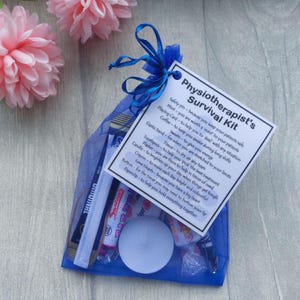 May include: A blue organza gift bag tied with a blue ribbon, containing a 'Physiotherapist's Survival Kit'. The kit includes a safety pin, mints, playing card, coffee, elastic band, sweets, toothpick, tissue, candle, plaster, crayon, button, Love Hearts, and paperclip.
