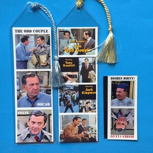 May include: Two clear plastic bookmarks with images from the TV show "The Odd Couple". The left bookmark features photos of Tony Randall and Jack Klugman, with the text "Felix" and "Oscar". The right bookmark features photos of the actors and the show's title, "Neil Simon's The Odd Couple". A third bookmark features a photo of Jack Klugman with the text "Dishes Dirty!" and "Dishes Clean!"