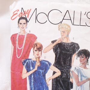 May include: Vintage McCall's sewing pattern featuring illustrations of four different dresses. The dresses are in red, blue, black, and white. The pattern includes the text "Easy McCall's" in a stylized font.