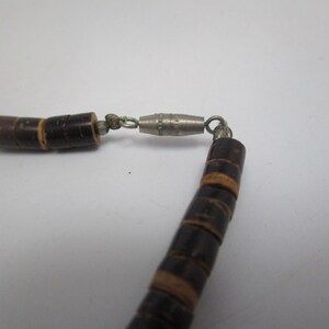 May include: A brown wooden bead necklace with a silver clasp. The beads are stacked and have a natural wood grain.