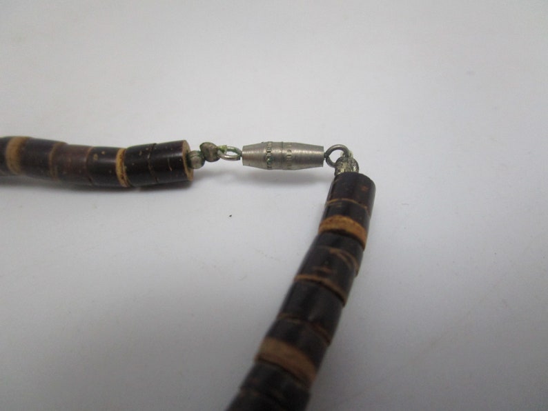 May include: A brown wooden bead necklace with a silver clasp. The beads are stacked and have a natural wood grain.