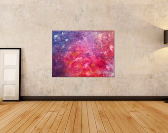 May include: Abstract painting with a vibrant mix of colors, including shades of pink, red, purple, and blue. The artwork is displayed on a wall in a room with wooden flooring and a floor lamp. The painting has the artist's signature.