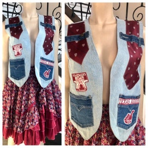 Könnte beinhalten: Eine hellblaue Jeansweste mit verschiedenen Patches und einer burgunderfarbenen Krawatte. Die Patches beinhalten die Worte "Texas Aggies" und eine Grafik einer Person, die einen Fußball hält. Die Weste hat zwei Fronttaschen und einen Knopfverschluss.