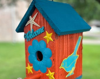 Casinha de passarinho personalizada, única, em estilo hippie groovy, nas cores laranja e turquesa, com decoração floral.