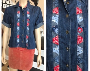 May include: A blue denim shirt with a short sleeve and a patchwork design of red, white, and blue fabric. The shirt has a button-up front and a collar.
