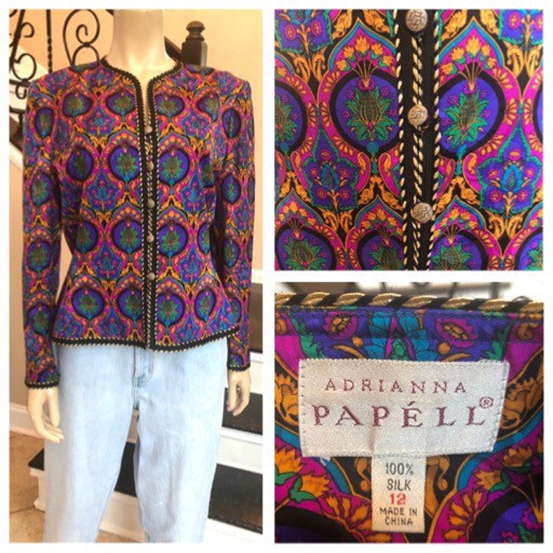 May include: Adrianna Papell silk jacket with a vibrant paisley pattern in shades of purple, blue, pink, and gold. The jacket has a black trim, long sleeves, and decorative buttons. The label reads "100% Silk, Size 12".
