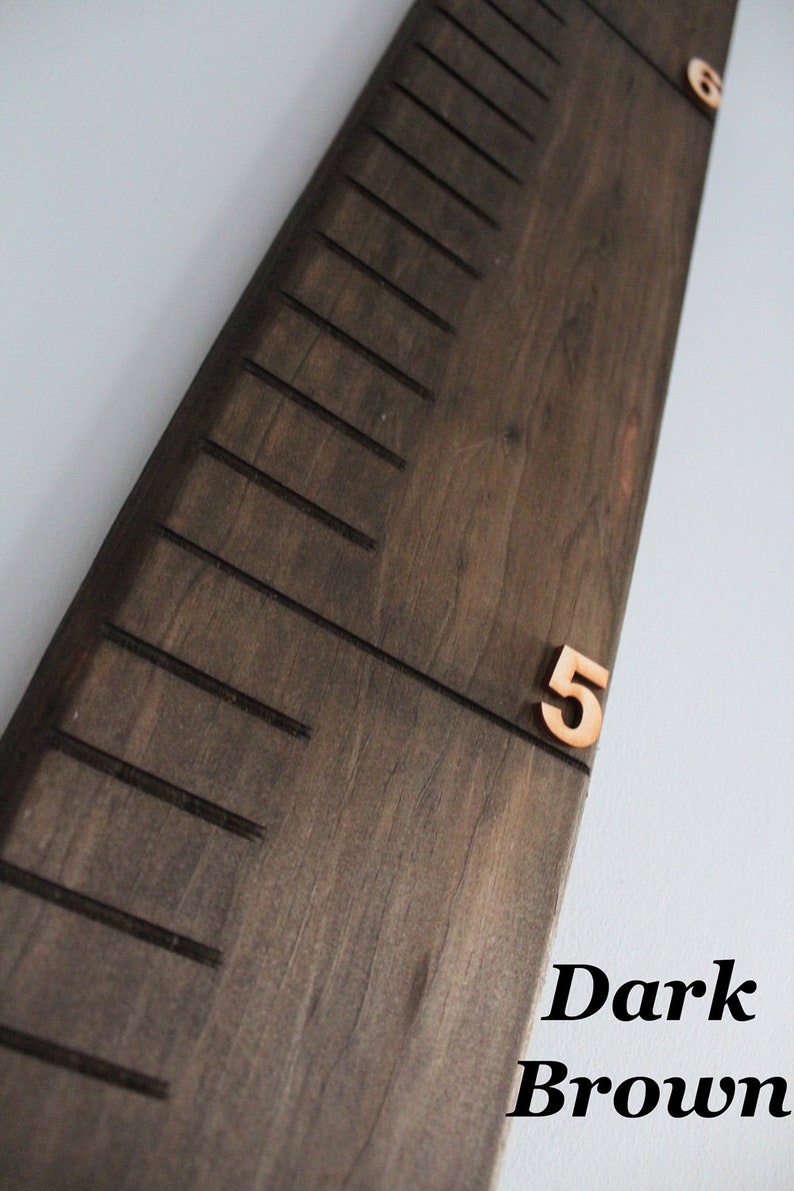 Pu&ograve; includere: Un grafico di crescita in legno marrone scuro con linee nere e numeri. Il numero "5" &egrave; visibile sul grafico.