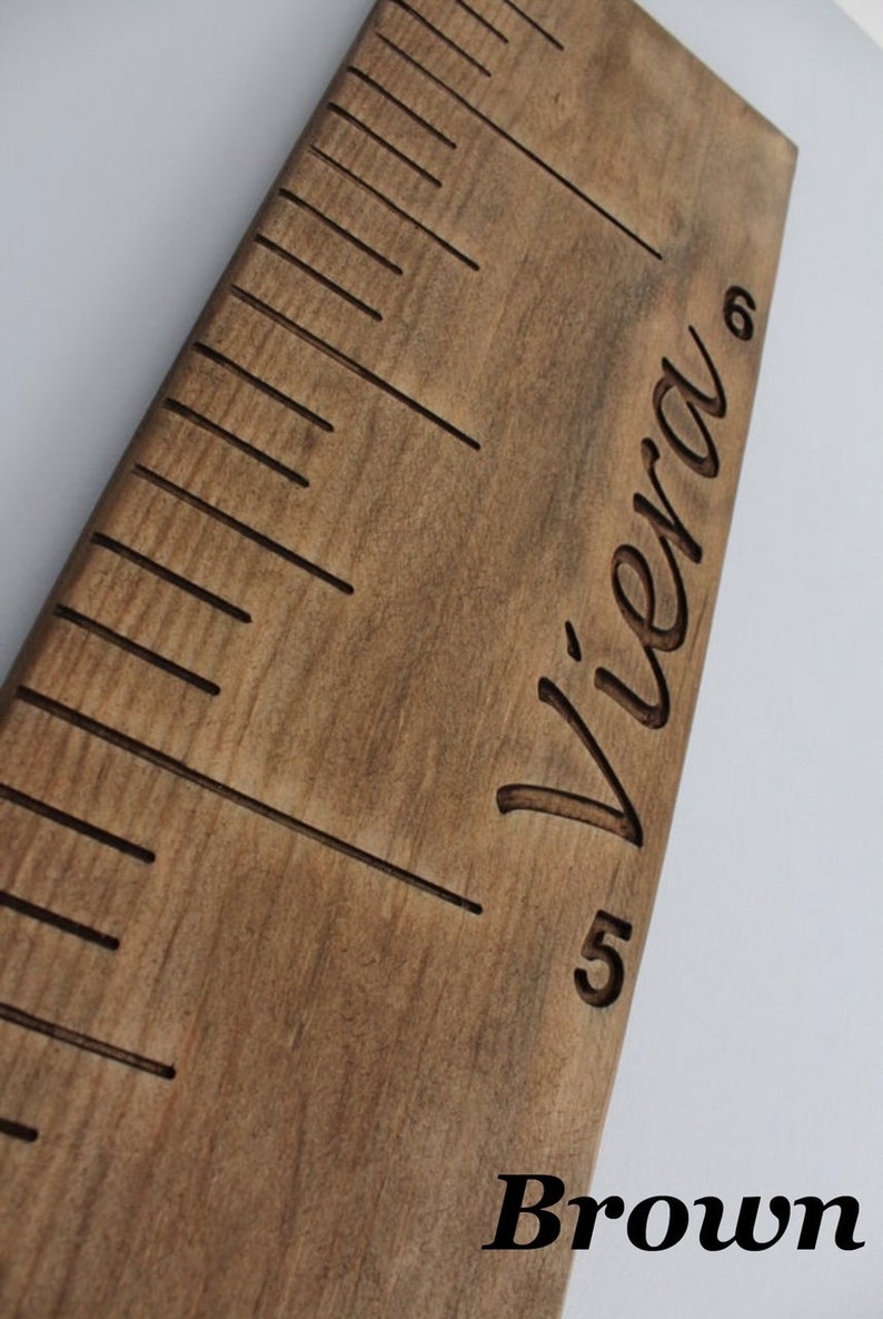 Pu&ograve; includere: Un grafico di crescita in legno marrone con un righello e il nome "Viera" inciso su di esso.