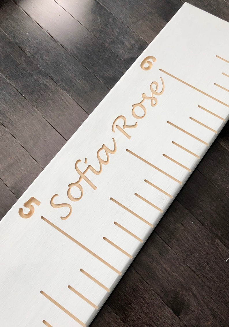 May include: White wooden growth chart with a gold inscription that reads "Sofia Rose" and a number "5" at the bottom.