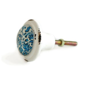 Peut inclure: Bouton de porte en céramique blanche avec un motif floral bleu et blanc. Le bouton est doté d'une vis en métal.