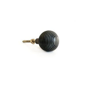 May include: Black wooden knob with a ribbed design and a brass screw.