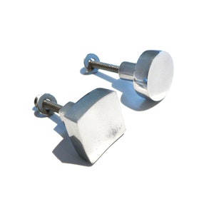 May include: Two silver cabinet knobs, one round and one square, with screws.