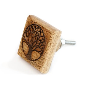 Op de afbeelding: Een vierkante houten kastknop met een gegraveerd boom des levens-ontwerp aan de voorkant. De knop heeft een zilveren metalen schroef.