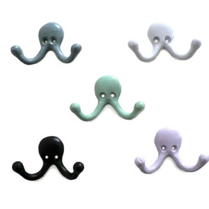 Könnte beinhalten: Fünf doppelte Haken in Octopusform in verschiedenen Farben: hellblau, weiß, hellgrün, lavendel und schwarz.