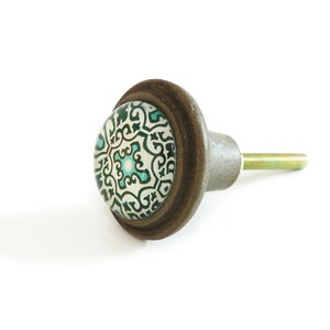 May include: A brown ceramic cabinet knob with a white and green patterned design.