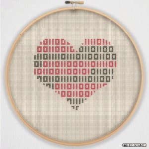 May include: A cross-stitch pattern of a heart made with red and black squares on a beige fabric. The heart is framed in a wooden hoop.