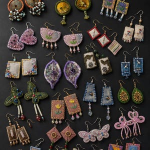 May include: A collection of various handmade fabric earrings featuring diverse shapes like hearts, butterflies, rectangles, and diamonds. These earrings are decorated with intricate embroidery, colorful beads, sequins, and metal hooks for hanging.