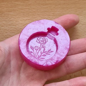 May include: A pink resin round tray with a floral design. The tray has a raised edge and a smooth surface.