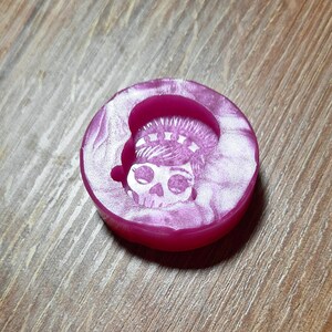 Könnte beinhalten: Eine rosa Silikonform mit einem weißen Design eines Schädels, der eine Krone trägt. Die Form ist zum Herstellen von Kunsthandwerk aus Harz.