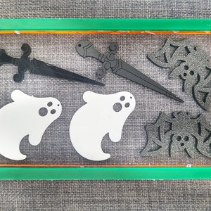 Könnte beinhalten: Ein Set an schwarz-weißen Halloween-Dekorationen. Das Set enthält zwei Geisterformen, einen Dolch und zwei Fledermausformen.