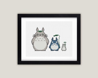Puede incluir: Un diseño de punto de cruz enmarcado con tres personajes de dibujos animados de la película animada Mi vecino Totoro. Los personajes son un Totoro gris grande con una hoja verde en la cabeza, un Totoro azul más pequeño y un pequeño Totoro gris con una hoja verde en la cabeza.