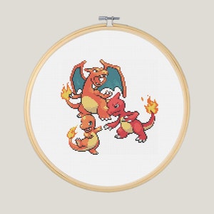 May include: A cross-stitch embroidery hoop with a white background and a colorful image of three Pokemon characters: Charizard, Charmeleon, and Charmander. The Pokemon are depicted in a pixelated style, with Charizard in the center, Charmeleon to the right, and Charmander to the left.