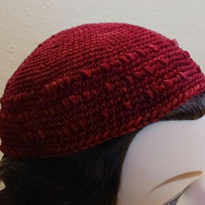 May include: A close-up of a red crocheted kippah, a traditional Jewish head covering.