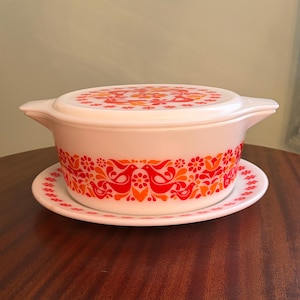 May include: A white ceramic mug with a black handle and the text "But First, Coffee" in a black, handwritten-style font. The mug is on a white surface.