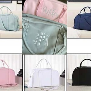 May include: Six different colour duffel bags with personalised embroidery. The bags are in pink, light blue, grey, white, and black. The embroidery on the bags reads "Wife", "JPK", and other initials.