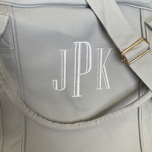 May include: A grey canvas tote bag with a white embroidered monogram "JPK" on the front.