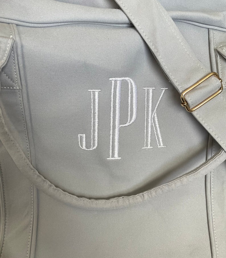 May include: A grey canvas tote bag with a white embroidered monogram "JPK" on the front.