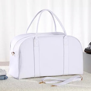 May include: White leather duffel bag with a top handle and a shoulder strap. The bag has two zipped compartments and a gold metal zipper pull.