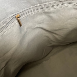 May include: The inside of a grey fabric bag with a gold zipper.