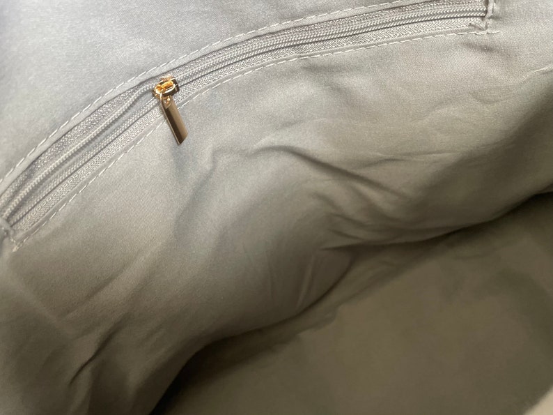 May include: The inside of a grey fabric bag with a gold zipper.