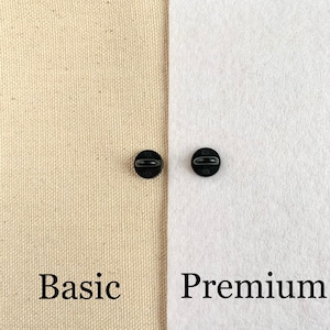 May include: Close-up of two black metal pin backs. The pin back on the left is labeled "Basic" and the pin back on the right is labeled "Premium".