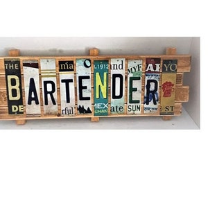 May include: A wooden sign with the word "BARTENDER" spelled out using vintage license plates. The sign is made of reclaimed wood and has a rustic look.